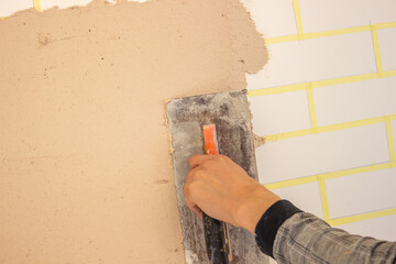 Hand with putty knife repair damaged wall