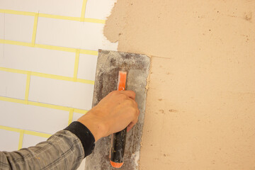 Hand with putty knife repair damaged wall