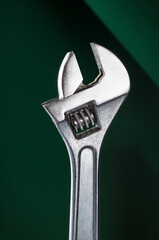 Adjustable wrench on dark green background.