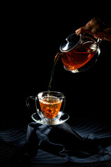 Pouring hot oolong tea to a cup on black backgrounds.
