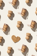Pattern with champagne corks and wooden cork heart on beige background with shadow at sunlight. Summer wine drinks concept, bottle cap of sparkling wine and metal wire muselet, repeat pattern