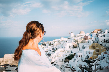Fototapeta na wymiar Junge Frau blickt auf Oia auf Santorin in Griechenland