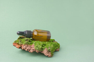 Natural skin care. Environmentally friendly cosmetics. brown glass jar with facial serum on the bark of a tree with green moss on a green background. copy space