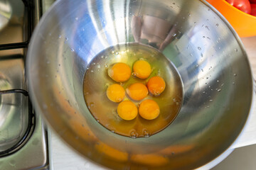 Eggs broken into a metal bowl with unbroken yolks