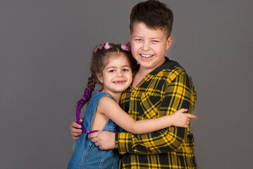 Brother and sister hug. Children on a gray background