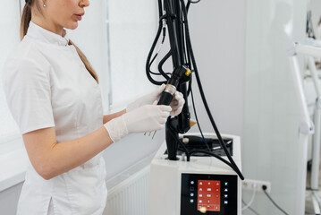 A cosmetologist sets up a modern device with a laser in a beauty salon. Laser pulses cleanse the skin. Hardware cosmetology. The process of photothermolysis, warming the skin.