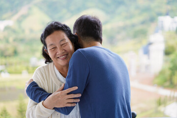Asian young son is hugging and smiling together with elderly mother in the morning time, concept of...