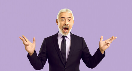 Wow it's amazing. Studio shot of senior businessman surprised by something extraordinary. White haired mature man in suit and necktie opens mouth and looks at camera with funny shocked face expression