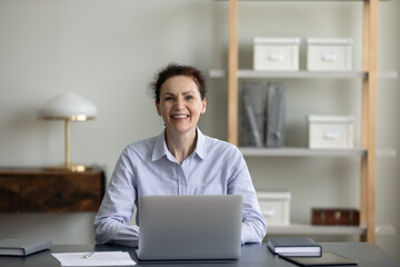 Happy senior business professional woman sitting at workplace, using laptop computer, looking at camera, smiling, laughing. Senior businesswoman, female executive corporate head shot portrait