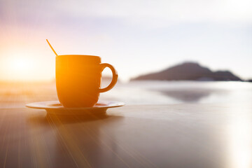 Coffee in a cup with the warm morning sea