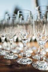 Row of empty champagne glasses on a table outdoors with sun reflection. Selective focus. Celebration concept