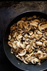 Fried sliced mushrooms, champignons in a pan on a  dark background, close up view
