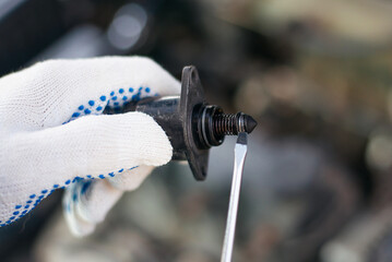 repair under the hood of a car with gloved hands and a screwdriver