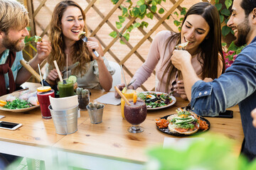 Young friends having fun eating brunch at healthy food restaurant - Focus on right girl face