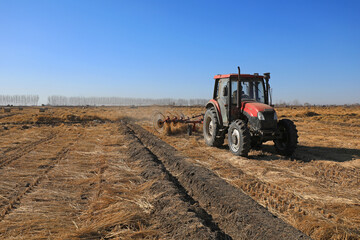 Fototapeta premium Farmers use a disc rake to collect straw in the field, North China