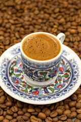 Turkish coffee in a classic coffee cup. Coffee beans background. close up