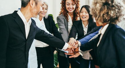 Multiracial business people celebrating together stacking hands inside modern office - Focus on...