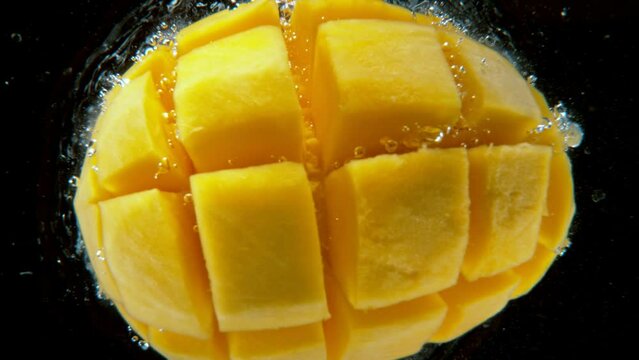 Fresh sliced mango falling into water, super slow motion filmed on high speed cinematic camera at 1000 fps.