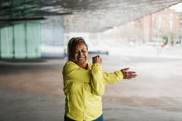 Senior african woman stretching during workout routine outdoor - Focus on face