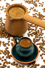 Turkish coffee on a white background. Rustic cup and earthen coffee pot. Scattered coffee beans on the ground