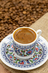 Turkish coffee on wood floor. Classic Turkish coffee cup on cloth. coffee beans in the background. Close up