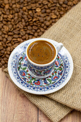 Turkish coffee on wood floor. Classic Turkish coffee cup on cloth. coffee beans in the background. Close up