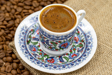Turkish coffee on wood floor. Classic Turkish coffee cup on cloth. coffee beans in the background. Close up