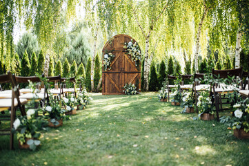 A beautiful area for an outdoor wedding ceremony. Arch Decorated with a large wooden door with many...