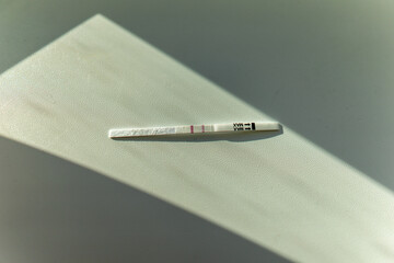 Pregnancy test in female hand on blurred background.