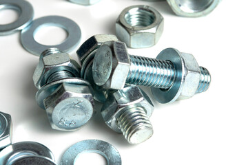 Several silver metal mounting bolts with nuts and washers on a white background. Close-up