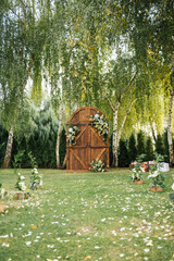 A beautiful area for an outdoor wedding ceremony. Arch Decorated with a large wooden door with many flowers.
