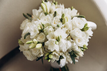 a beautiful wedding bouquet of white flowers and greenery stands in a chair
