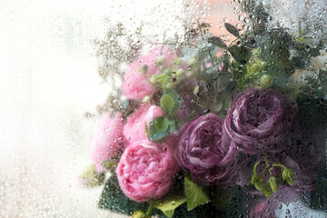 Fresh still life. A vase of flowers outside the window. Water drops after rain on the glass....