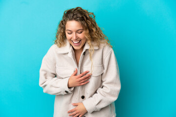 Young blonde woman isolated on blue background smiling a lot