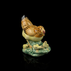 antique figurine of an easter hen with little chicks on a black isolated background