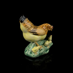 antique figurine of an easter hen with little chicks on a black isolated background
