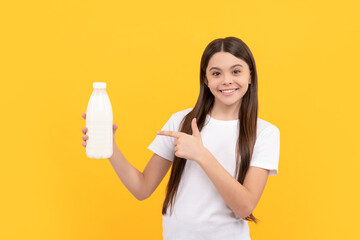 happy child pointing finger on dairy beverage product. teen girl going to drink milk.