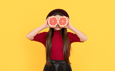 smiling kid behind grapefruit on yellow background, antioxidants