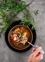 Hand holding a spoon with a shrimp and fish, Seafood Diet soup