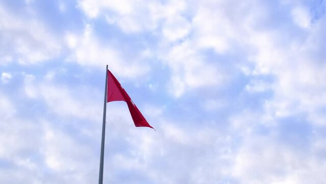Turkish flag waving in blue sky with clouds , Republic Square in Antalya. A lively town square with equestrian statue of former President Ataturk surrounded by numerous cafes.