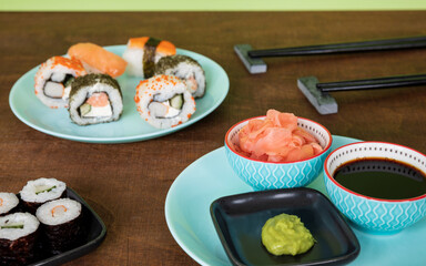Sushi condiments set in bowls: wasabi paste, soy sauce and pickled pink ginger.