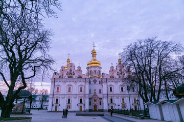 Fototapeta na wymiar Medieval Gate Church of the Trinity of Kyiv Pechersk Lavra. View of east facade from the monastery side on a background of blue sky with clouds in winter. 