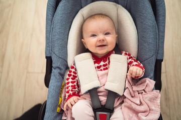 Small baby sitting in a car seat, baby girl, smiling baby, white baby