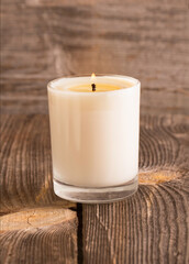 Fototapeta na wymiar burning candle in glass on wooden background