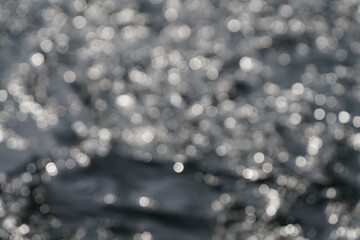 Fließendes Wasser in einem Fluss und mit Sonnenlicht, welches sich im Wasser spiegelt und reflektiert