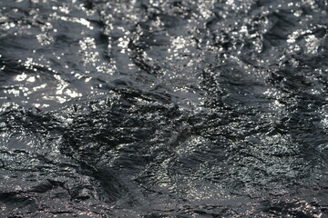 Obraz premium Fluss mit schnell fließendem Wasser und sich darin spiegelndem Sonnenlicht