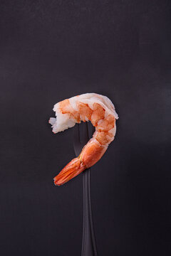 One shrimp on a fork on a black background