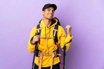 African American man with backpack and trekking poles over isolated background pointing to the side to present a product