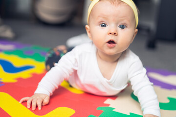 6 month old baby girl lying on the number colourful puzzle