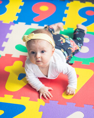 6 month old baby girl lying on the number colourful puzzle